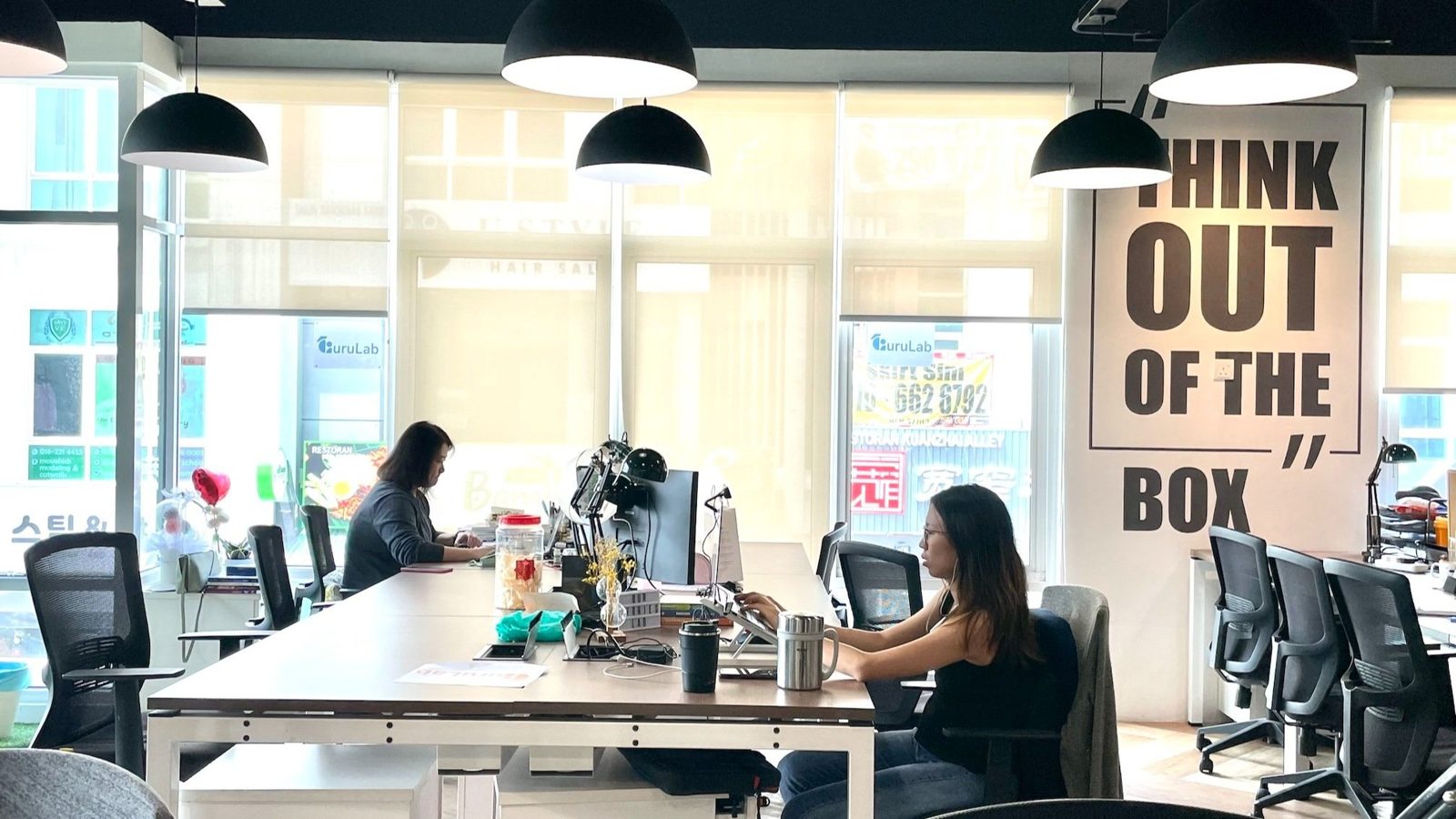 Fixed desk coworking zone at Sandbox Space with members at work